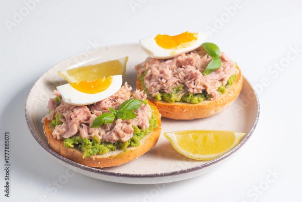 Fototapeta Two delicious tuna open sandwiches with avocado and boiled eggs. Tuna toast.