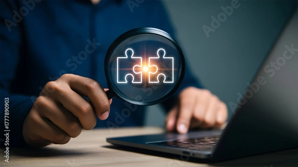 Obraz Magnifying Glass Focusing on Two Interlocking Puzzle Pieces on Laptop Solution Concept
