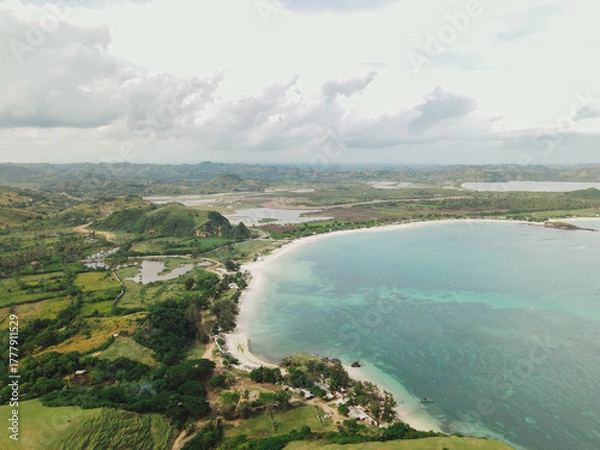 Fototapeta The coastal view is surrounded by enchanting green hills, including Merese Hill, which offers a spectacular viewpoint to enjoy the scenery. LOMBOK, NTB , INDONESIA