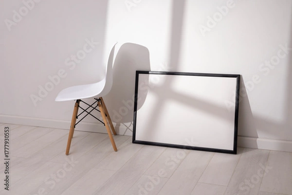 Obraz Mockup of empty frame in modern minimalist interior with chair and morning light on white wall background. Template for artwork, painting, photo or poster