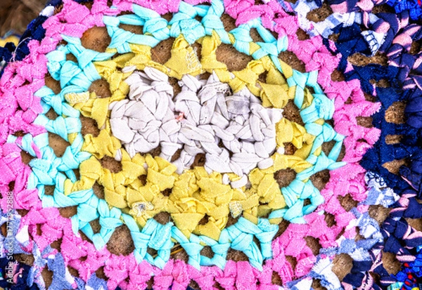 Fototapeta Vintage homespun doormat made from strips of cloth as background. Texture of a homemade rug from different fabrics. Round knit mat