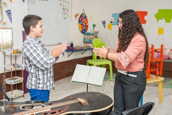 Obraz Guitar teacher and young student standing and clapping hands to learn rhythm and timing during a private music lesson. Concept of musical training, coordination, and interactive learning