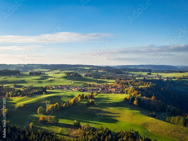 Obraz Rolling Bavarian hills in golden autumn, tranquil Morgenbach village and patchwork farms under vast blue sky, ideal for rural tourism ads.