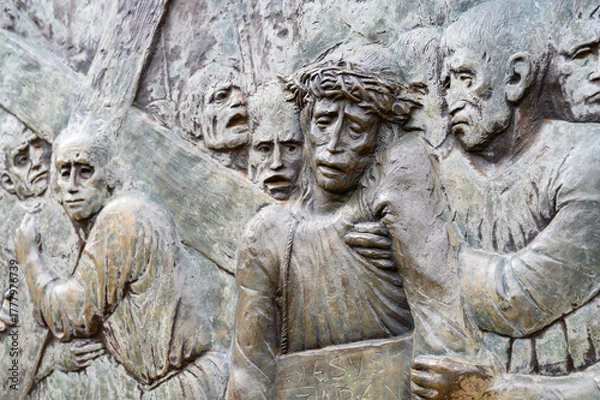 Obraz Station V: Simon of Cyrene helps Jesus carry the Cross. The Way of the Cross on Mount Križevac (the Cross Mountain) in Medjugorje.