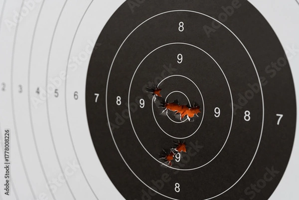 Fototapeta Bullet holes clustered in the center bullseye of a paper shooting target. Marksmanship, precision, and accuracy concept.