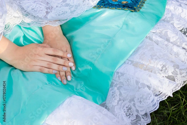 Fototapeta Detail of the delicate hands of an unrecognizable woman wearing a blue dress with copy space in Neiva, Huila, Colombia