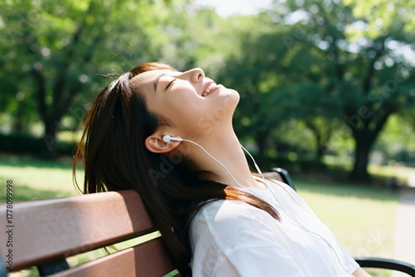 Fototapeta Woman enjoying music in a park with eyes closed