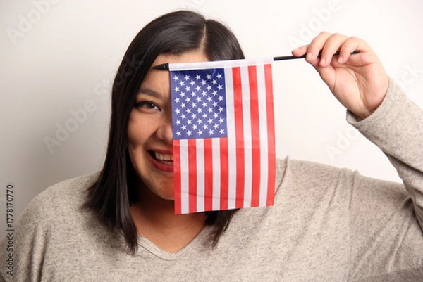 Obraz 40-year-old Latina woman proudly displays the United States flag as a symbol of migration and freedom