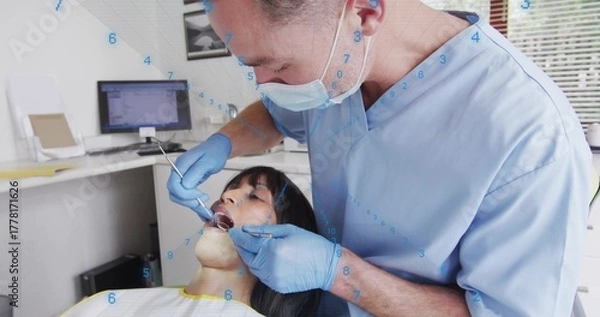 Obraz Leaning male dentist in scrubs examining teeth at dental clinic, with mouth mirror and dental probe