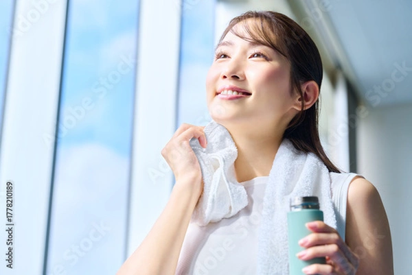 Obraz ジムで汗を拭く笑顔の女性　撮影協力：スポーツクラブ&サウナスパ ルネサンス 幕張24