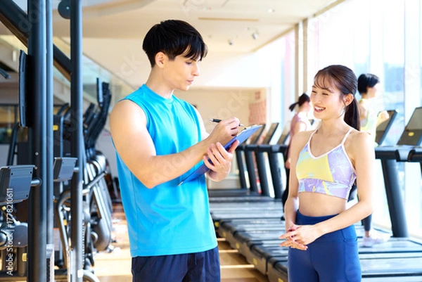 Obraz ジムでパーソナルトレーニングの計画について話すトレーナーと女性　撮影協力：スポーツクラブ&サウナスパ ルネサンス 幕張24