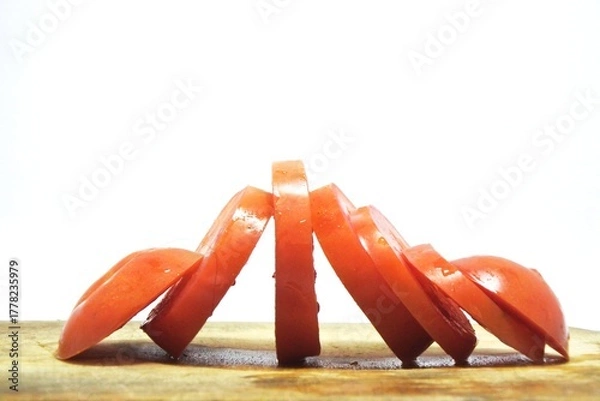 Obraz Fresh red tomato slices, solanum lycopersicum or lycopersicum esculentum on an old wooden cutting board photographed on the isolated white background