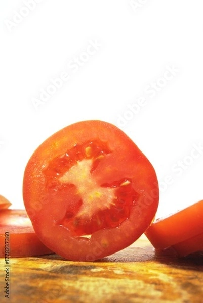Obraz Fresh red tomato slices, solanum lycopersicum or lycopersicum esculentum on an old wooden cutting board photographed on the isolated white background
