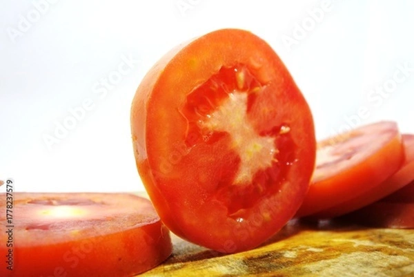 Obraz Fresh red tomato slices, solanum lycopersicum or lycopersicum esculentum on an old wooden cutting board photographed on the isolated white background