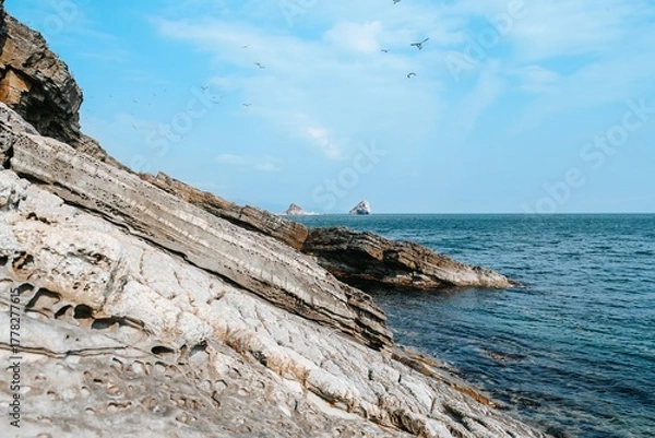 Fototapeta Rocky coastal landscape at Desantnaya Bay in Vladivostok, Russia, overlooking the blue waters of the Japanese Sea under a clear winter sky.
