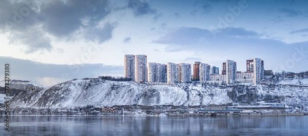 Fototapeta A modern winter landscape featuring urban architecture beautifully situated by the serene river