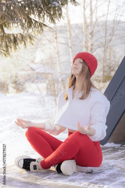 Obraz Serene young woman meditating in lotus position amidst a peaceful snowy forest, practicing mindfulness and finding zen during a winter retreat.