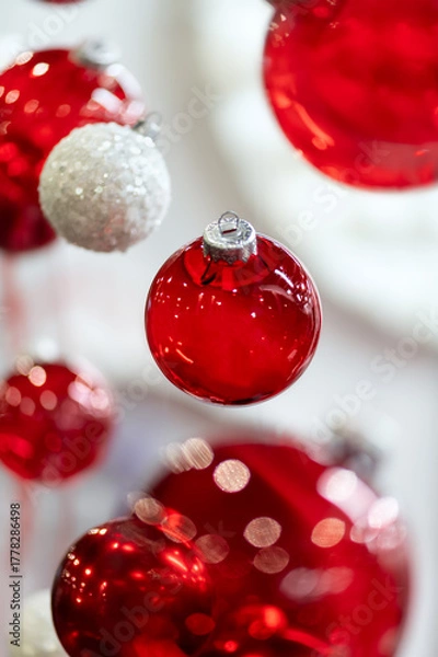 Obraz Red and white glass Christmas baubles hanging in vertical composition