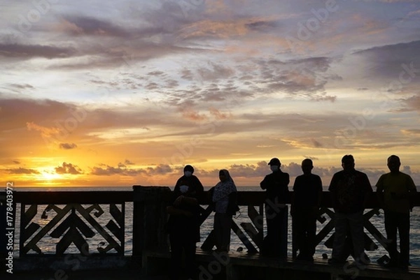 Fototapeta A number of tourists enjoy the beautiful sunset on the beach