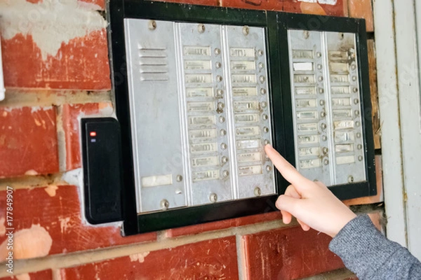 Fototapeta Young girl talking on the intercom and presses the button