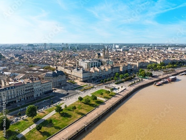 Fototapeta A drone shot showcases the beautiful cityscape of Bordeaux, France, highlighting its historic architecture, the Garonne River, and the lively quayside promenade.