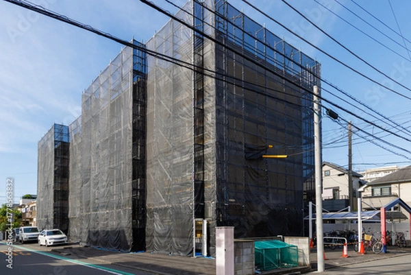 Obraz 外壁工事のために黒いネットで覆われた集合住宅