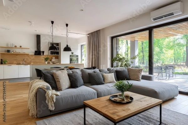 Fototapeta Modern Living Room with Gray Sectional Sofa Near Window and Wooden Accents Featuring Natural Light with Hardwood Floor and Views of Green Foliage Outdoors