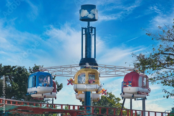 Fototapeta 子どもたちに大人気のローカルな遊園地は、カラフルな乗り物がいっぱい