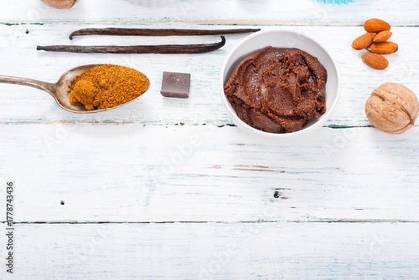 Fototapeta pile of brown sugar on old spoon, vanilla, broken dark chocolate blocks on white wooden table