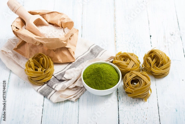Fototapeta uncooked taglatelle pasta and ingredients: grounded spinach powder and whole wheat flour