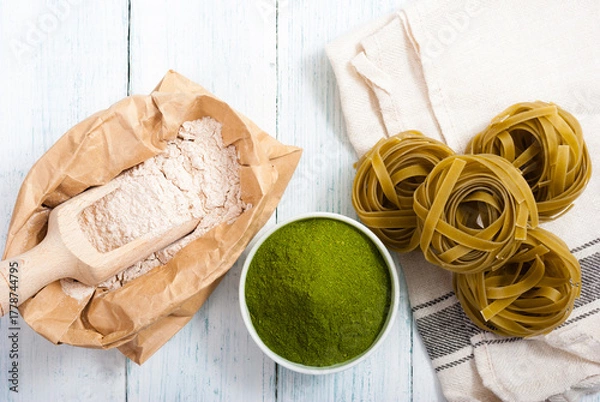 Fototapeta uncooked taglatelle pasta and ingredients: grounded spinach powder and whole wheat flour