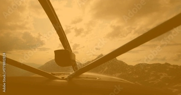 Fototapeta Displaying support struts and cockpit instrument panel top through windshield, with water droplets