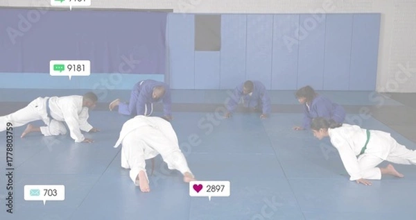 Fototapeta Crawling martial artists wearing training jackets, colored belts across dojo mat with overlay icons