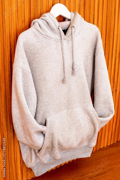 Fototapeta Stylish Light Gray Hoodie Hanging Against Natural Wood Background