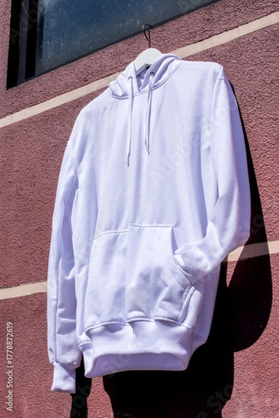 Fototapeta Stylish White Hoodie Mockup on Hanger Against Vibrant Wall Ready for Your Design Perfect for Fashion