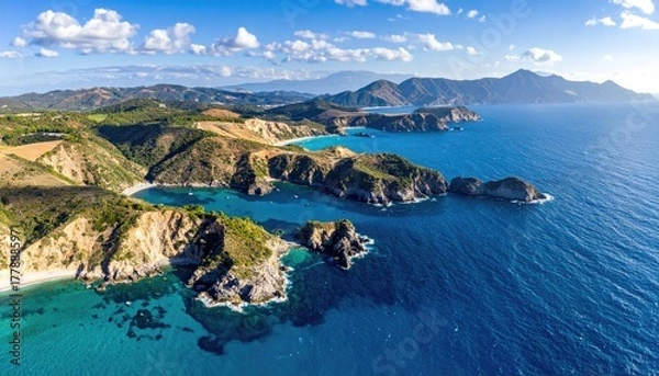 Fototapeta Expansive Coastal Landscape With Jagged Cliffs And Turquoise Waters Under a Bright Blue Sky With Wispy Clouds