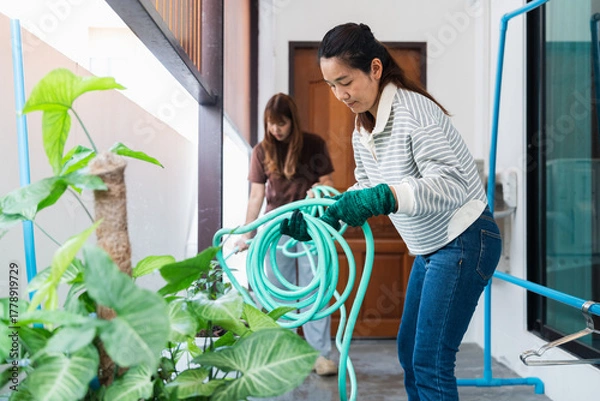 Fototapeta Asian woman enjoys sustainable living by gardening at home with eco friendly practices in bright lifestyle setting nurturing green plants with care and focus