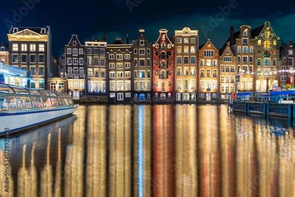 Fototapeta Amsterdam night. Colorful houses canal water reflection. Evening street architecture with lights in windows lanterns. Old multi colored Building.