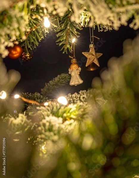 Fototapeta Christmas ornaments hanging on pine branches with blurred lights