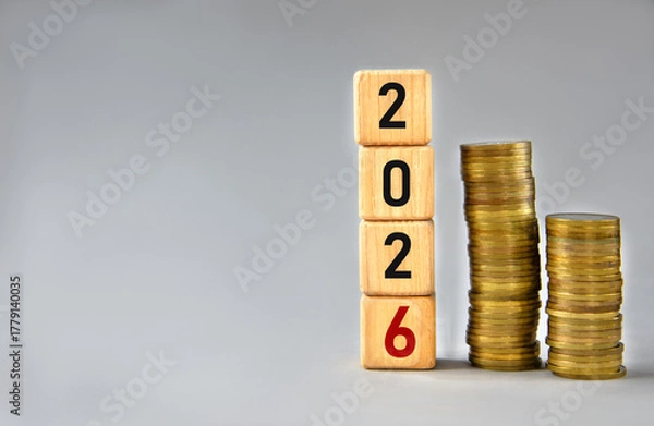 Fototapeta 2026 - numbers on wooden cubes against a background of stacks of coins