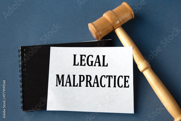Fototapeta LEGAL MALPRACTICE - words on a white sheet on a black notebook with a judge's gavel in the background
