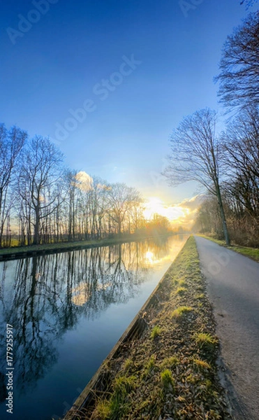 Fototapeta A serene riverside scene at dawn, showcasing the exquisite beauty of nature with its vibrant reflections on water