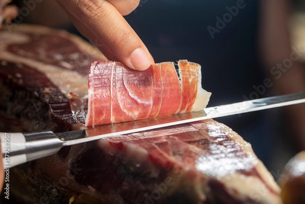 Obraz Slicing Iberian ham close up with knife