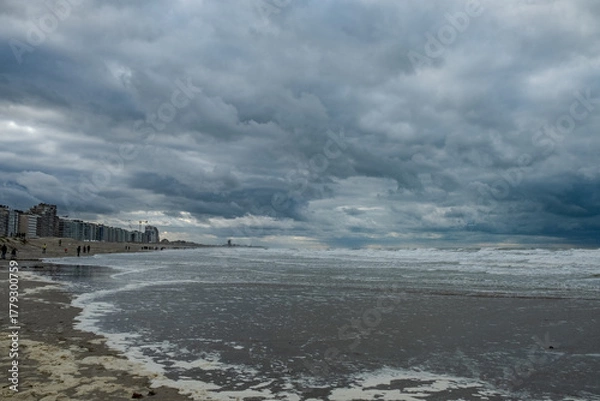 Fototapeta Nieuwpoort, West-Vlaanderen, Belgium, Ocotber 25th, 2025, vast and desolate beachscape under heavy cloud cover with textured wet sands and feeling