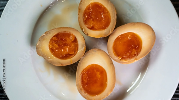 Fototapeta Soy-marinated ajitsuke tamago eggs halved on a plate, revealing creamy, succulent yolks. Perfect for ramen topping or appetizer. Rich, flavorful, and authentic.