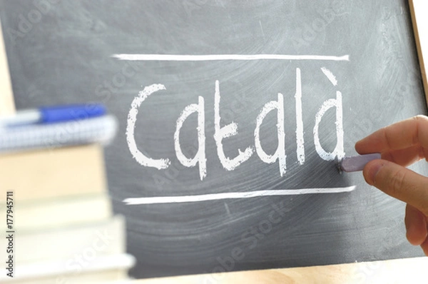 Obraz Hand writing on a blackboard in a language class with the word CATALAN wrote on. Some books and school materials.