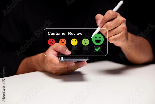 Fototapeta A person providing feedback using a mobile device, showcasing a customer review interface with emoticons for various satisfaction levels.