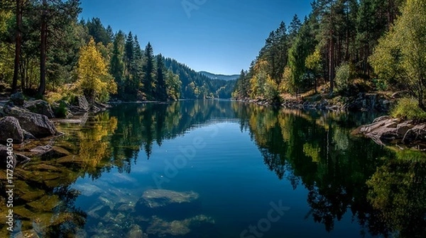 Fototapeta Discover a stunning lake surrounded by vibrant autumn foliage reflecting in the calm water under a clear blue sky perfect for outdoor adventures