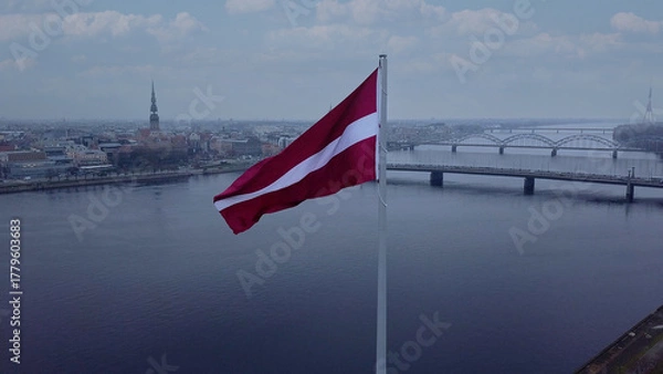 Fototapeta Drone View Of Riga Old Town With Latvian Flag Waving In Foreground Aerial Panorama Of Historic City Center, Daugava River And Urban Skyline On A Outumn Day In Latvia