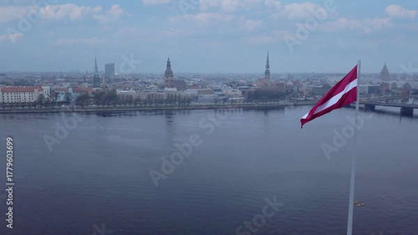 Fototapeta Drone View Of Riga Old Town With Latvian Flag Waving In Foreground Aerial Panorama Of Historic City Center, Daugava River And Urban Skyline On A Outumn Day In Latvia